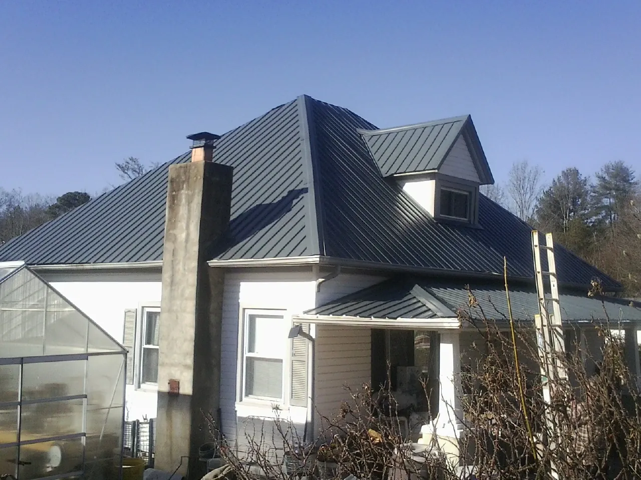 Dark blue standing seam metal roof on a white farmhouse with dormer — Slate & Tile Roof Repair by Roofing Brothers in Santa Ana