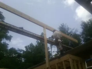 Carpenter setting a ridge beam over a new addition frame — Ice Dam Removal by Roofing Brothers in Santa Ana