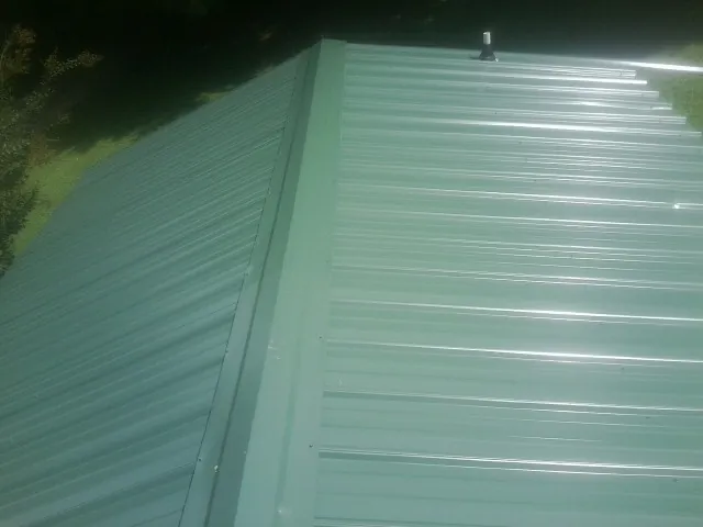 New green metal panels meeting at the ridge of a roof — Flat Roof Repair work by our crew in Santa Ana