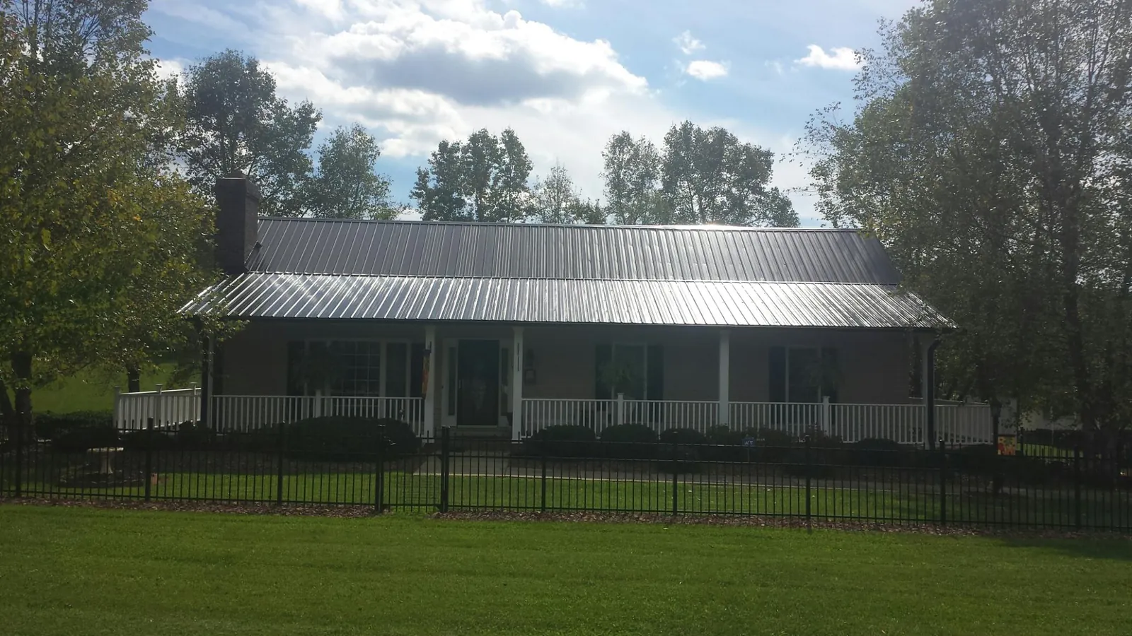 Gray metal roof on a brick ranch with a full width front porch — Gutter Guard Installation work by our crew in Santa Ana