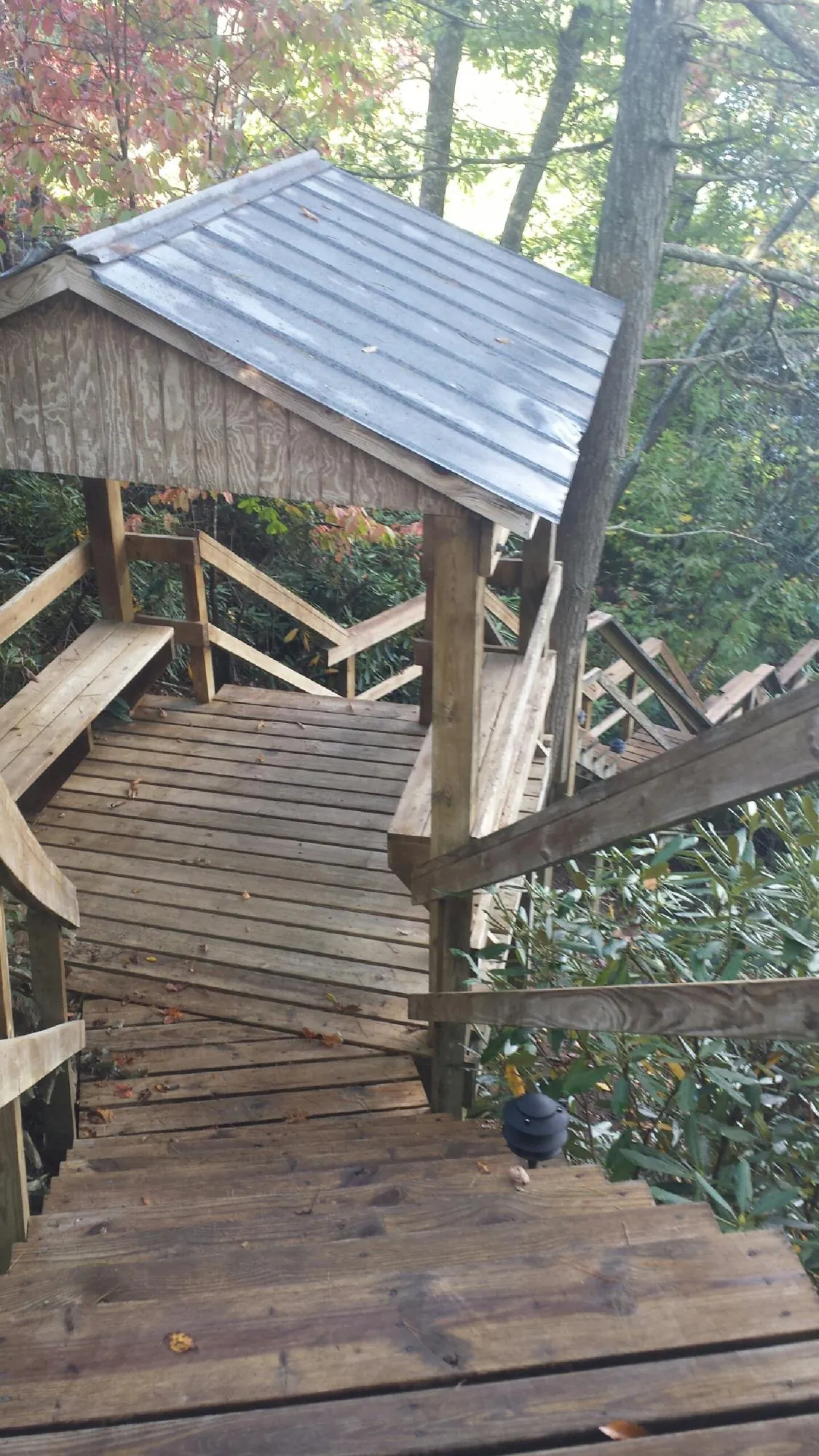 Metal roofed shelter over wooden steps on a wooded walkway — Skylight Repair & Installation work by our crew in Santa Ana