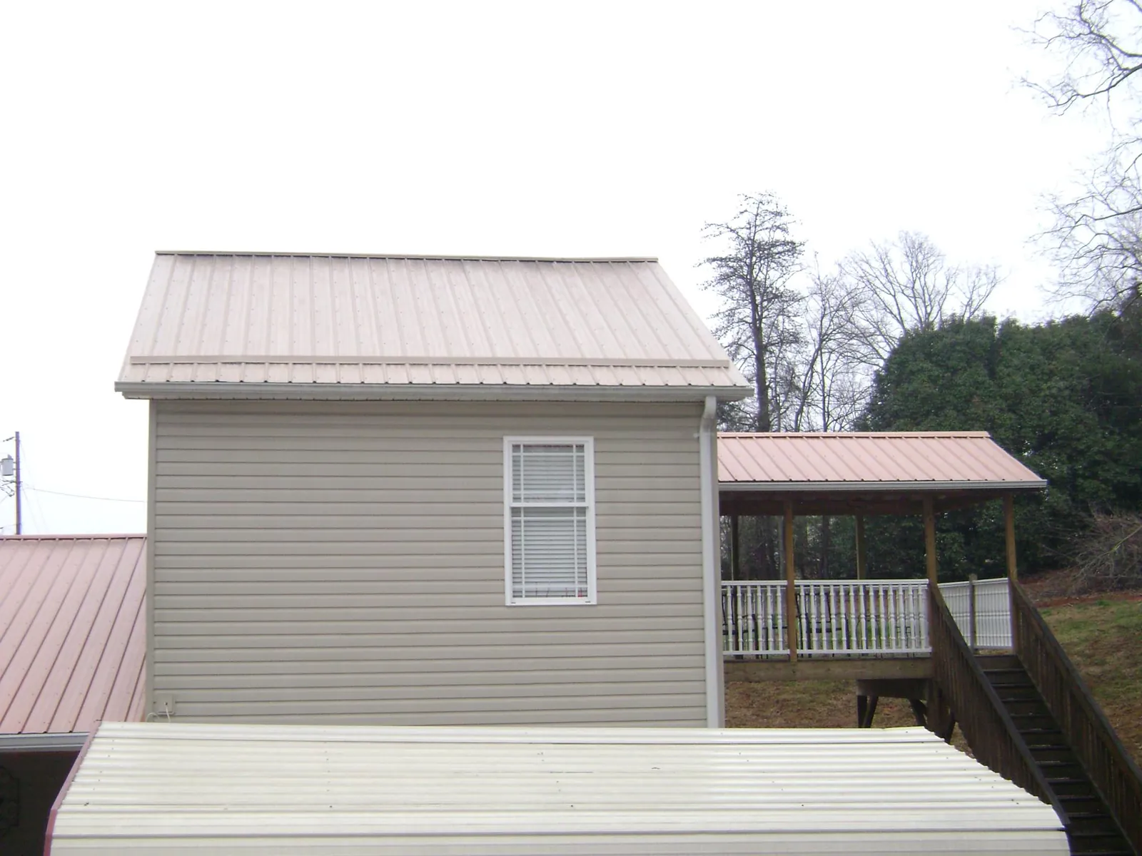 Tan metal roofs on a two story addition and attached porch, from a Roof Replacement job in Santa Ana