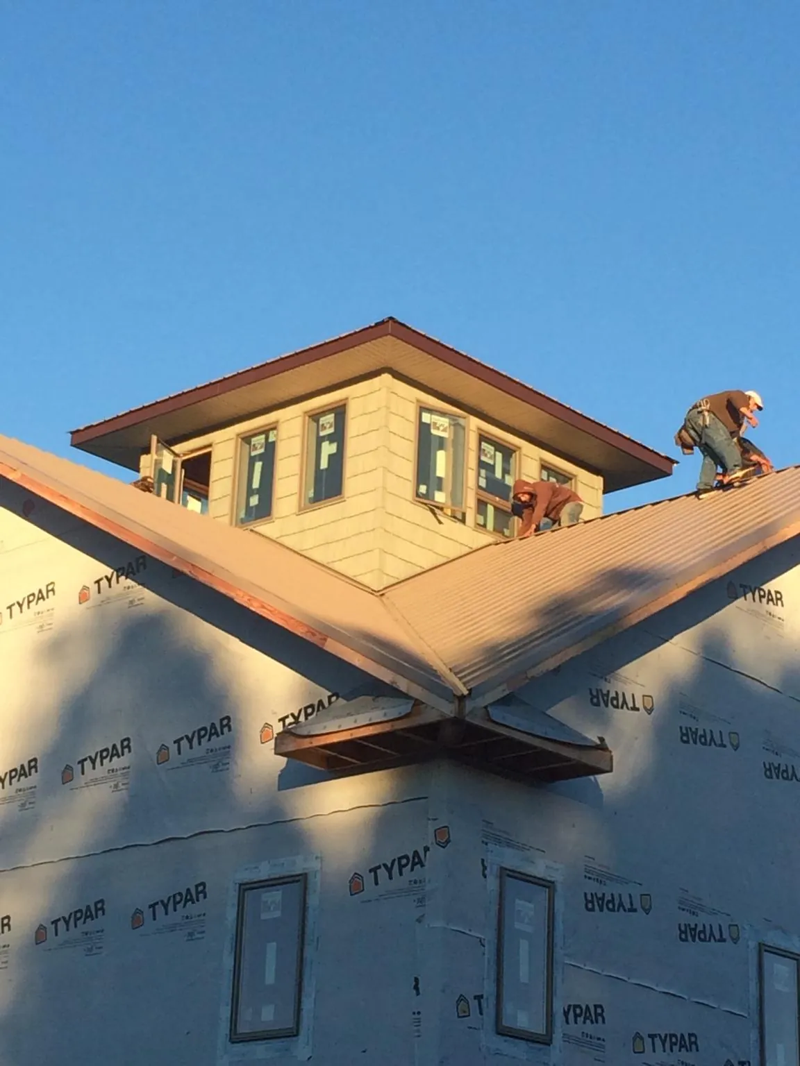 Roofers working around a rooftop cupola on a new metal roof at sunset — Roof Waterproofing in Santa Ana by Roofing Brothers